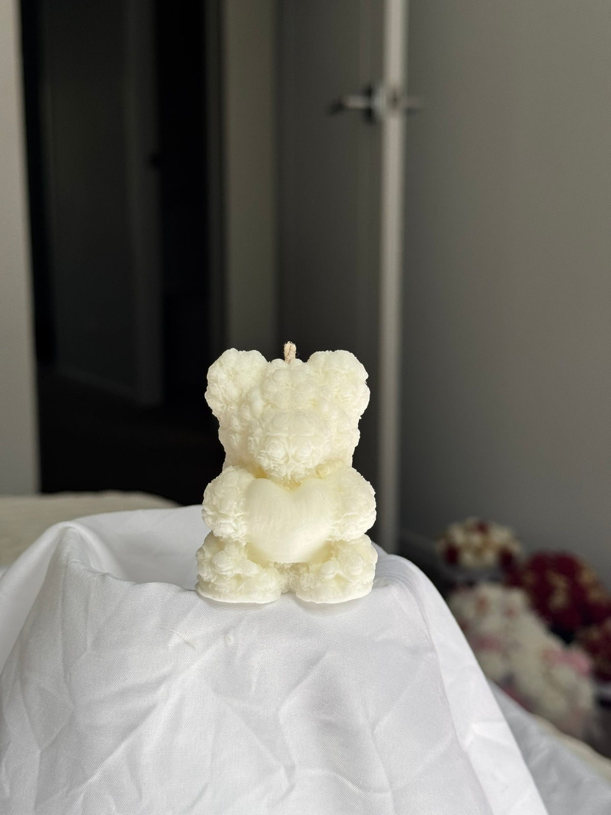 Sculpted ivory bear candle covered in tiny roses, holding a heart