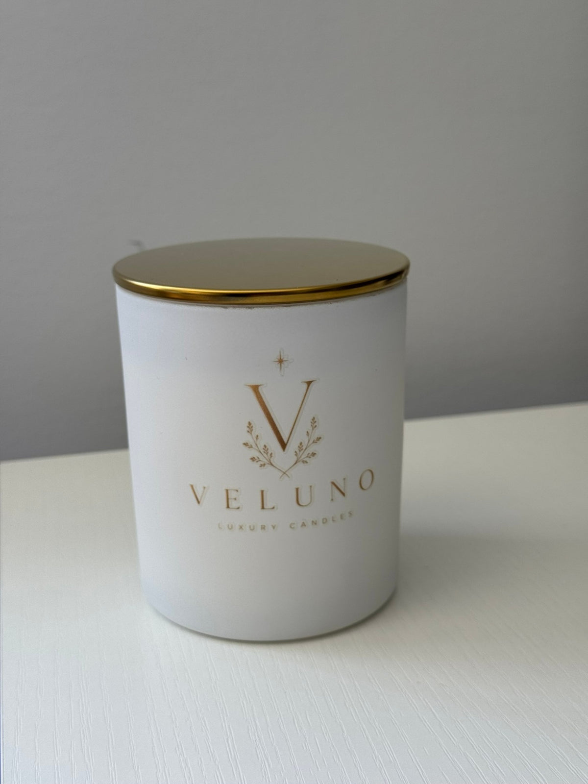 Veluno Alabaster — matte white jar candle with a gold lid and the Veluno monogram