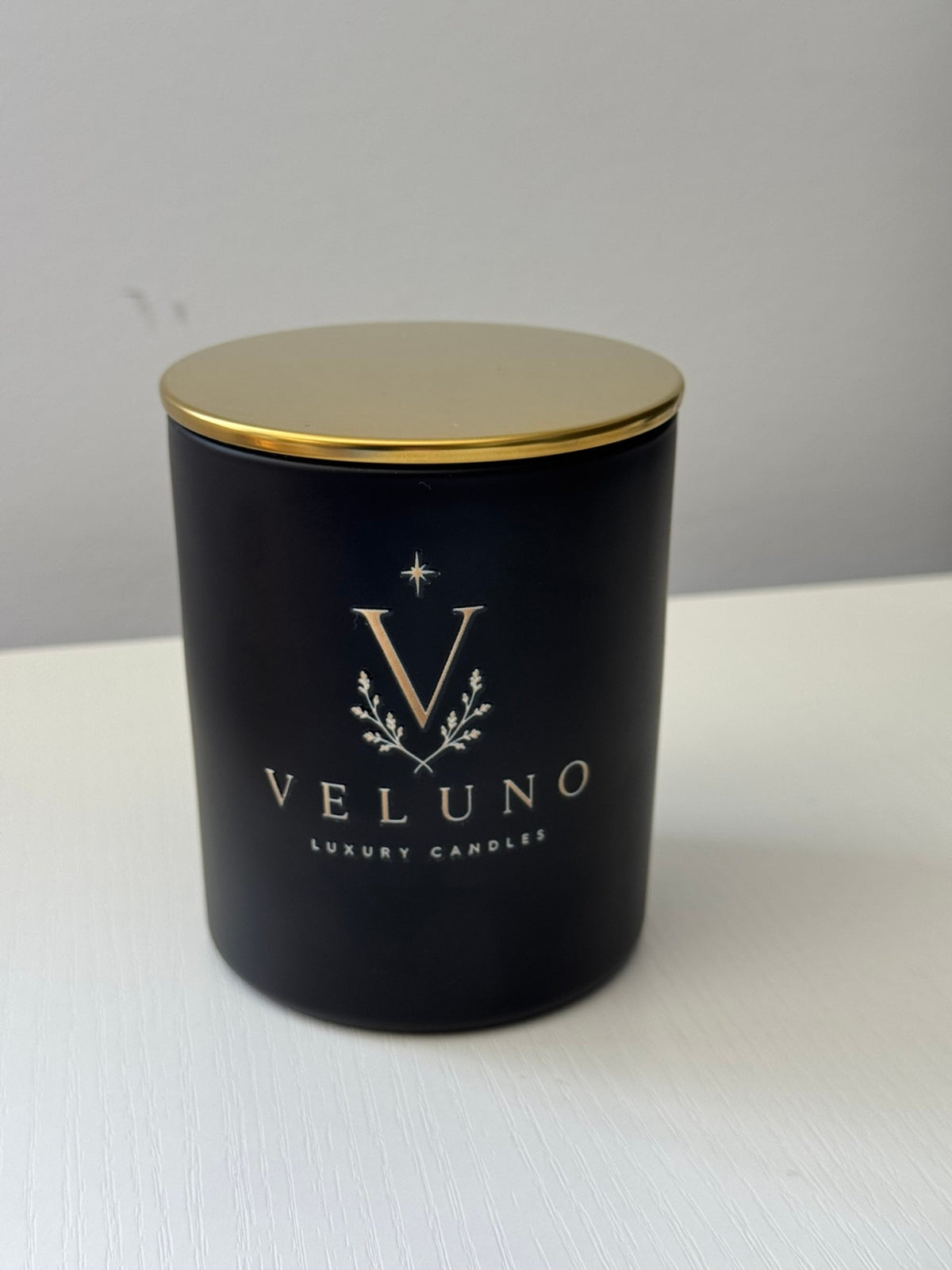 Veluno Obsidian — matte black jar candle with a gold lid and the Veluno monogram